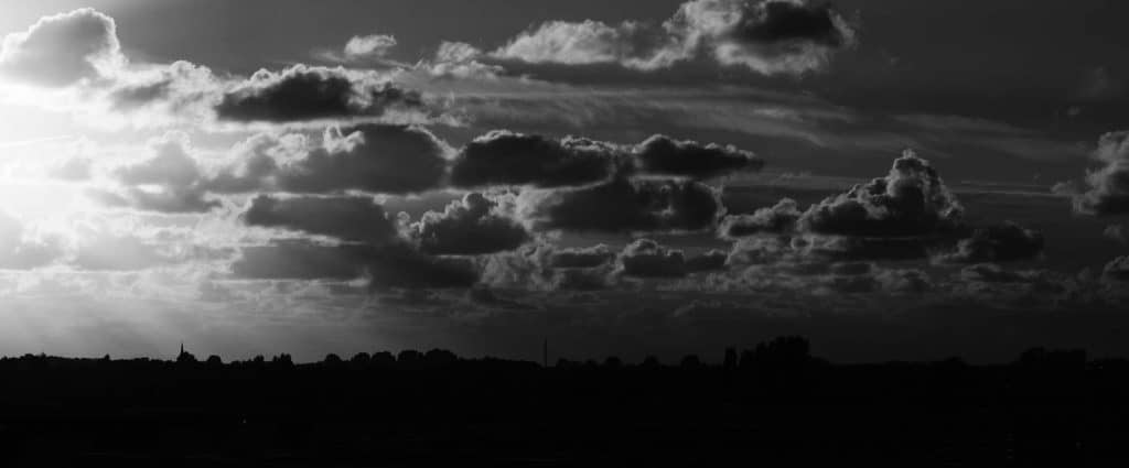 A black and white image of a landscape is highlighted by the sun creeping in from the left.